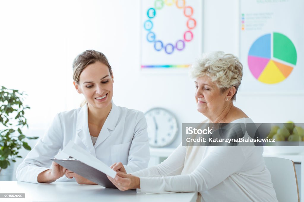 Nutrizionista sorridente che mostra il piano dietetico - Foto stock royalty-free di Medico