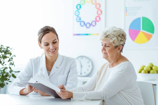 nutrizionista sorridente che mostra il piano dietetico - medicine lab coat hospital senior adult foto e immagini stock