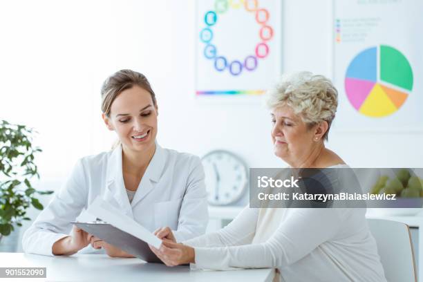 Smiling Nutritionist Showing Diet Plan Stock Photo - Download Image Now - Doctor, Nutritionist, Patient