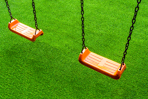 Double vivid orange color Swing seat on the artificial grass school yard