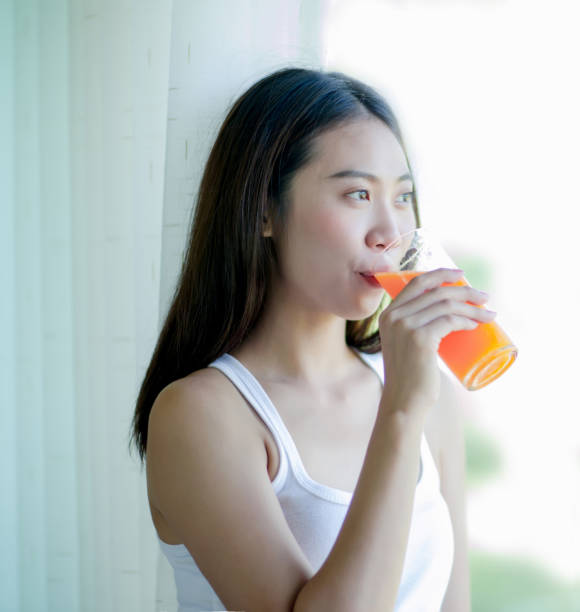 istock Asian girl drinking orange juice 901568318