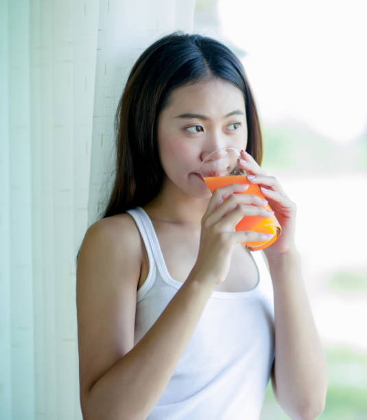 istock Asian girl drinking orange juice 901568322