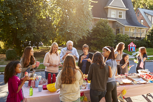 Vecinos hablaran y comen alrededor de una mesa en una fiesta de bloque photo