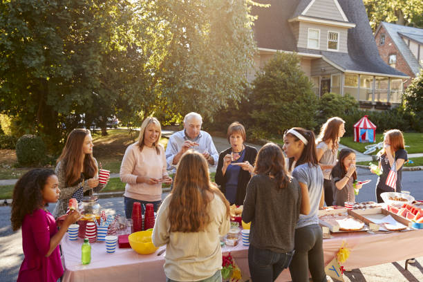 vecinos hablaran y comen alrededor de una mesa en una fiesta de bloque - fiesta callejera fotografías e imágenes de stock