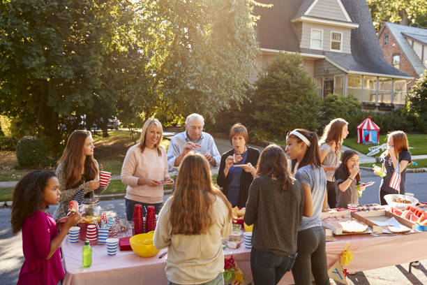 istock Neighbours talk and eat around a table at a block party 901570232