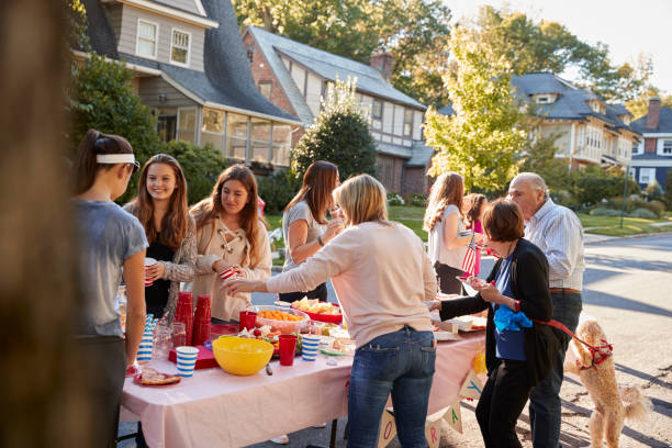 istock Neighbours talk standing around a table at a block party 901570688