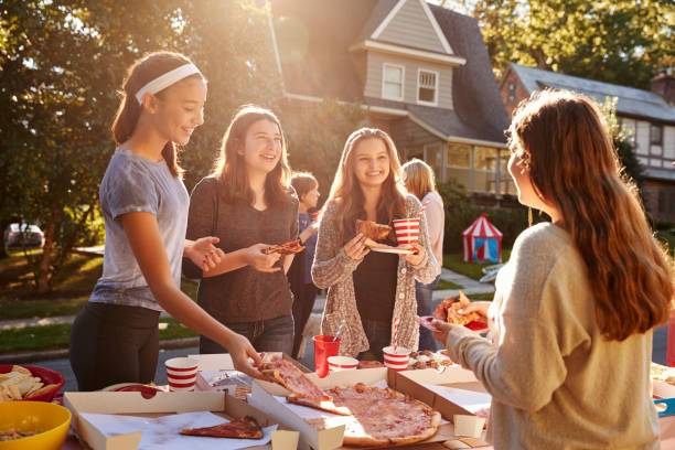 adolescentes comiendo pizza y hablando en un partido del bloque - fiesta callejera fotografías e imágenes de stock