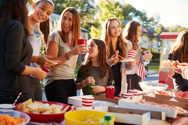 las chicas están hablando en una mesa de comida de parte de bloque, cerca - fiesta callejera fotografías e imágenes de stock