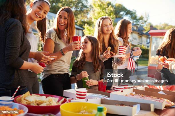 Girls Stand Talking At A Block Party Food Table Close Up Stock Photo - Download Image Now