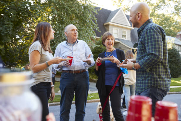 vicini di mezza età e anziani che parlano a una festa di blocco - vicino di casa foto e immagini stock