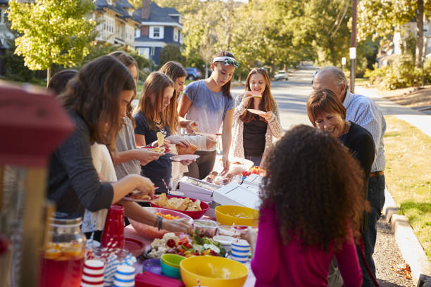 voisins, debout autour d’une table à une fête de quartier - fête de rue photos et images de collection