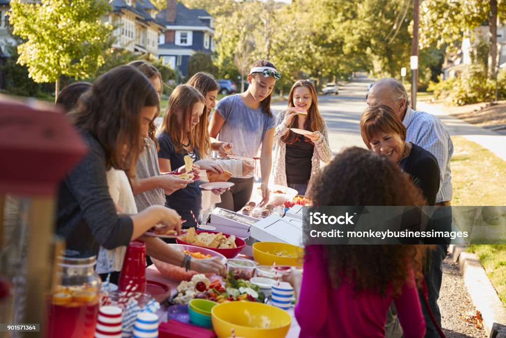 Vicini in piedi intorno a un tavolo a una festa di blocco - Foto stock royalty-free di Festa di strada