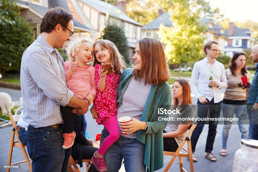 Genitori che tengono i loro figli piccoli mentre mangiano a una festa di blocco - Foto stock royalty-free di Vicino di casa