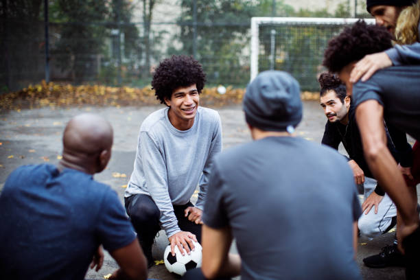 Smiling soccer player planning strategy with team Smiling soccer player discussing strategy with team. Friends are huddling together on field. They are in sportswear. soccer team captain stock pictures, royalty-free photos & images