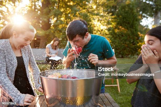 Friends Watch Teenage Boy Apple Bobbing At Garden Party Stock Photo - Download Image Now
