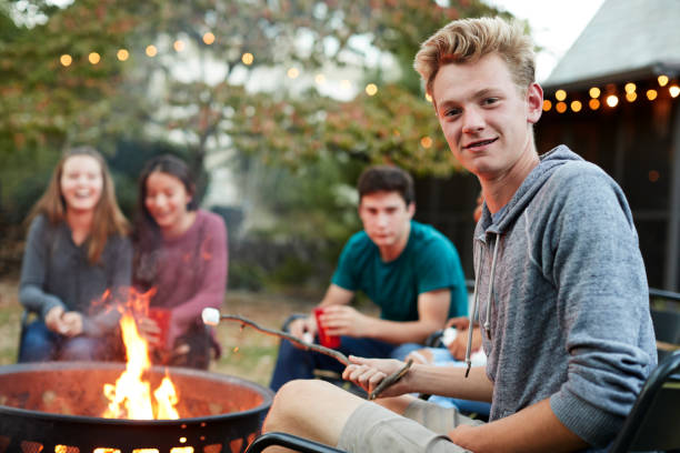 nastoletni chłopiec z przyjaciółmi tosty marshmallow w ognisku - fire pit fire fireplace outdoors zdjęcia i obrazy z banku zdjęć