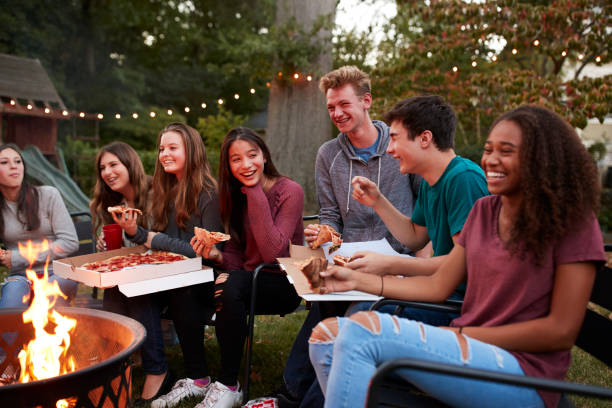 adolescentes en un fogón comiendo pizzas para llevar, cerrar - pizza party fotografías e imágenes de stock