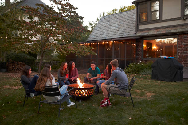 nastolatki siedzą rozmawiając wokół ogniska w ogrodzie o zmierzchu - fire pit fire fireplace outdoors zdjęcia i obrazy z banku zdjęć