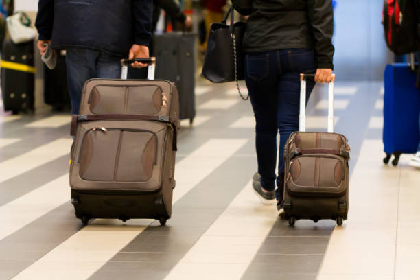 istock Couple pulling the suitcases in airport. 901572598