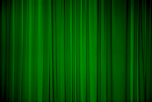 Green fabric background. Draped curtain hanging close-up. Christmas texture for design. Decorative Wallpaper or Web Banner With Copy Space.