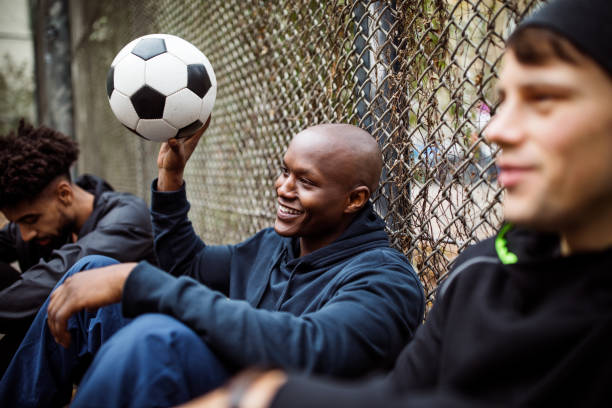 istock Player sitting with his soccer team against fence 901575112