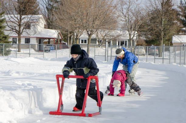 istock Mother teaching daughter how to ice skate while young boy uses a helping accessory 901580492