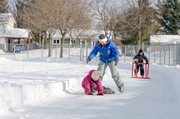 istock Mother teaching daughter how to ice skate while young boy behind uses a helping accessory 901582714