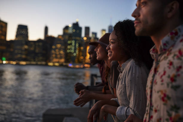 group of young friends on trip to manhattan at dusk - manhattan new york city night skyline imagens e fotografias de stock
