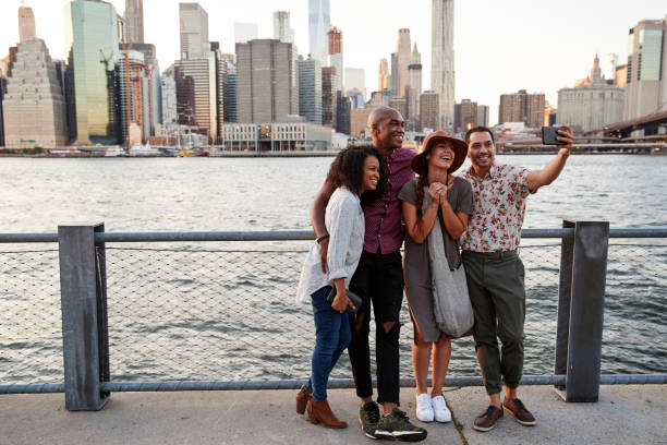 gruppo di amici in posa per selfie di fronte allo skyline di manhattan - american holiday foto e immagini stock