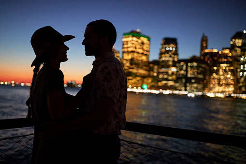Silhouette Of Romantic Couple With City Skyline In Background