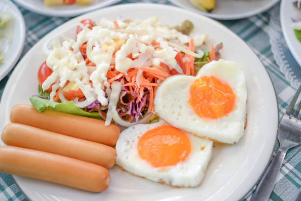 English breakfast with fried eggs, bacon, sausages, beans, toasts and fresh salad