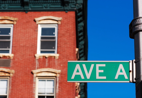Isolated shot of Avenue A street sign in Lower East side of Manhattan  with  beautiful blue sky and building in  background out of focus