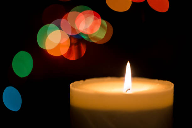 istock Burning candle with multi colored bokeh and black background 901609302
