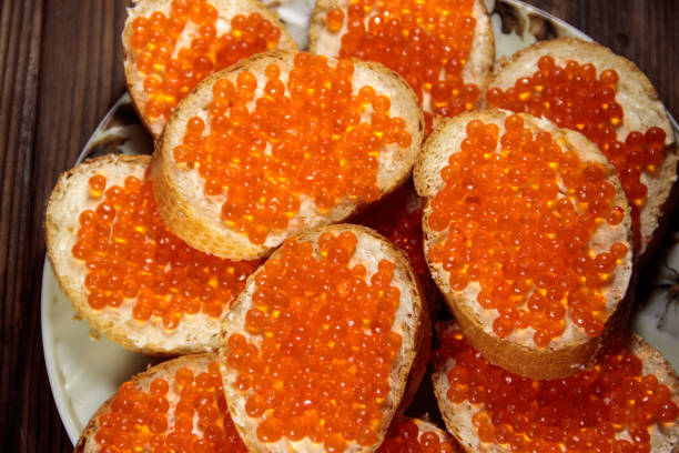 sandwiches con mantequilla y caviar rojo en mesa de madera - plank bread caviar close up fotografías e imágenes de stock