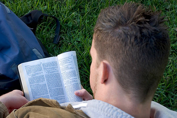 Man reading a book on the grass from a high angle view stock photo