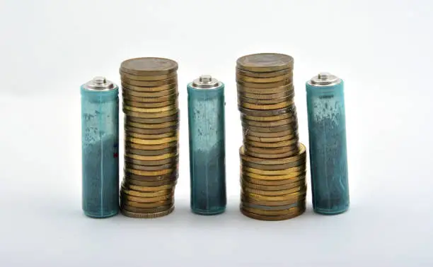 Photo of Three AAA batteries with coins isolated on white background