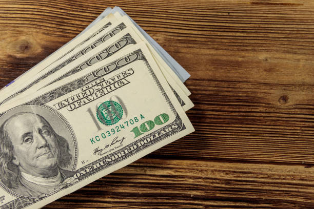 istock Stack of one hundred dollars bills on wooden desk 901622270