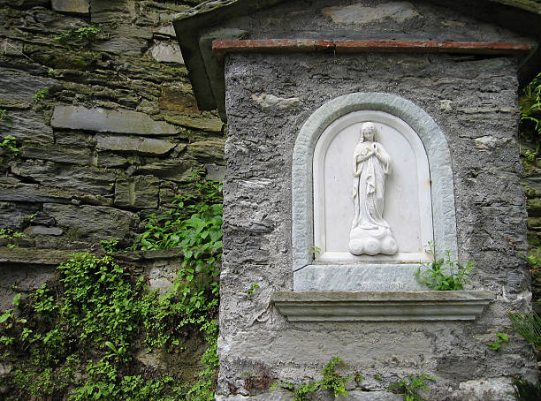 Mature hispanic woman praying at outdoor statue
