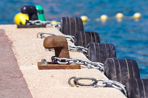 Old metal dock mooring pole with ring and rope for securing fishing boats .