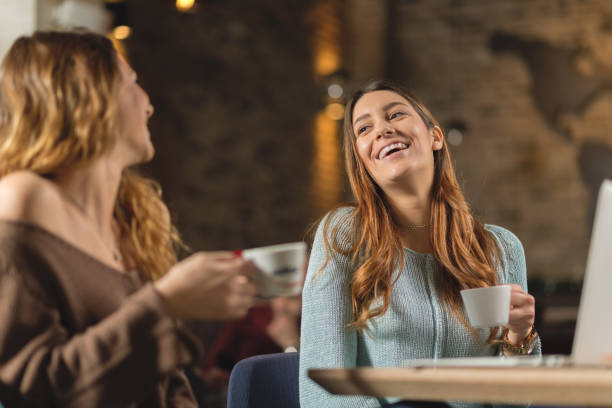 istock Young cheerful women talking to each other at cafe 901634734
