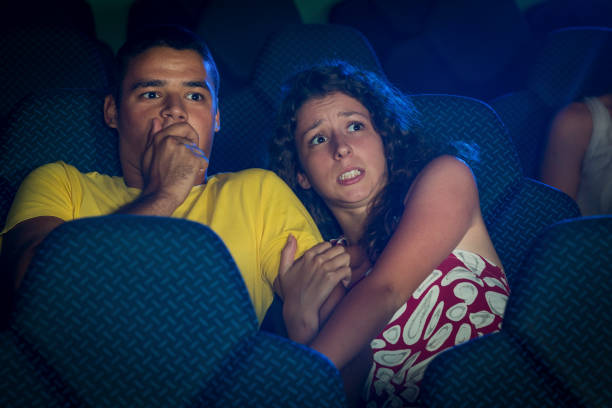 couple watching a horror movie in a cinema - audience surprise movie theater shock imagens e fotografias de stock