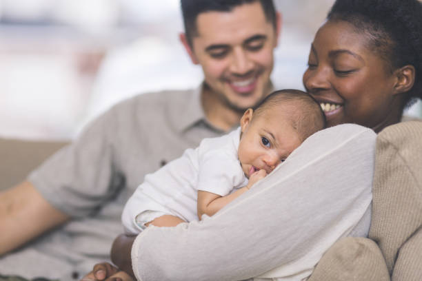 nouvelle maman tient son bébé sur sa poitrine - mixed race person photos et images de collection