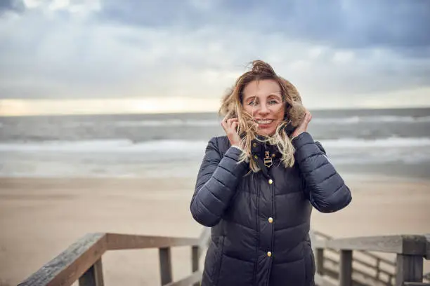 Photo of Middle-aged woman braving a cold winter day at the sea