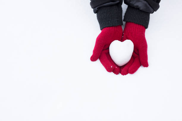 woman holding heart-shaped snowball, close-up of hands - glove winter wool touching imagens e fotografias de stock