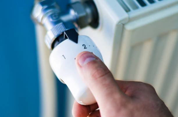 One hand adjust Radiator thermostat valve close up stock photo