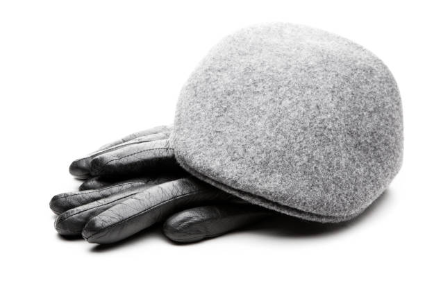 istock Tweed grey cap black leather gloves white background 901732978