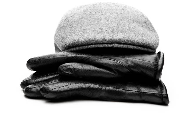 istock Tweed grey cap black leather gloves white background 901732988