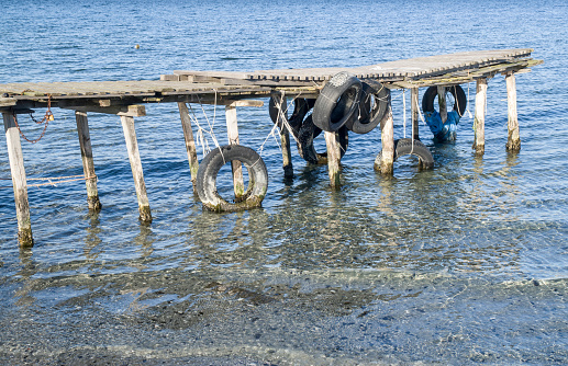 Old wooden small pier with tire in the lake