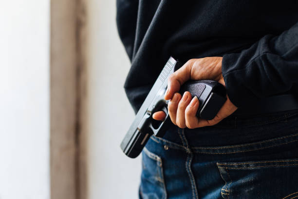 istock Criminal and robbery concept. Robber pulls out a gun tucked in his jean. 901762564