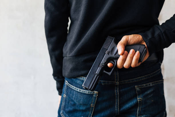 istock Criminal and robbery concept. Robber pulls out a gun tucked in his jean. 901762586